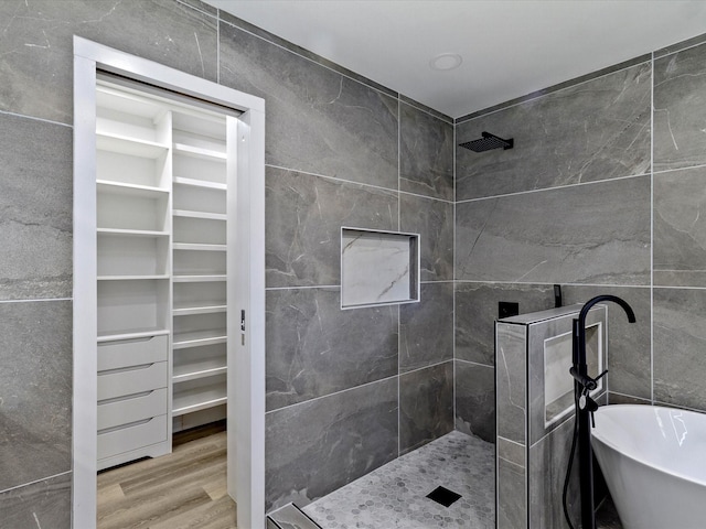 bathroom with hardwood / wood-style flooring, plus walk in shower, and tile walls