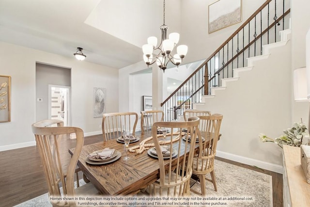 dining area with a high ceiling, an inviting chandelier, and wood-type flooring