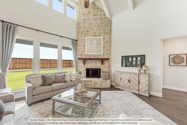 living room featuring high vaulted ceiling, hardwood / wood-style floors, beamed ceiling, and a stone fireplace