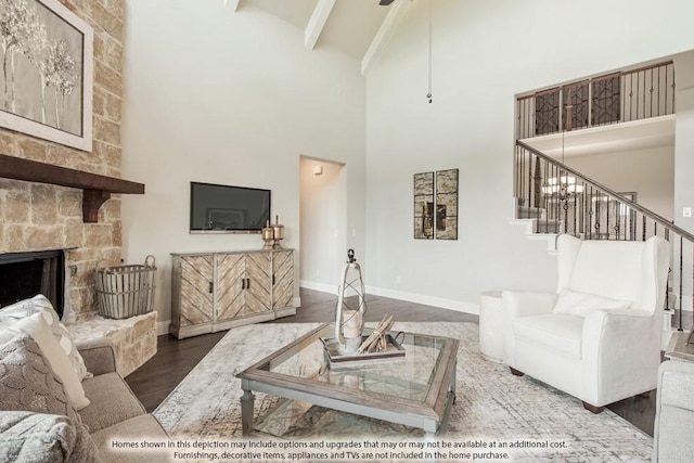 living room with hardwood / wood-style floors, a stone fireplace, a towering ceiling, and beam ceiling