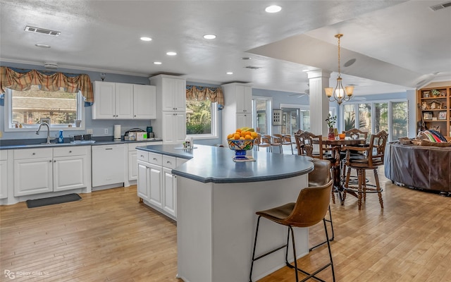 kitchen featuring light hardwood / wood-style floors, white cabinetry, white dishwasher, and pendant lighting