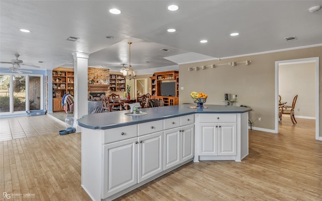 kitchen with light wood-type flooring, ornate columns, white cabinets, and ceiling fan