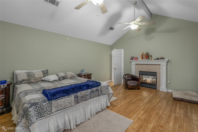 bedroom with hardwood / wood-style flooring, beam ceiling, ceiling fan, high vaulted ceiling, and a fireplace