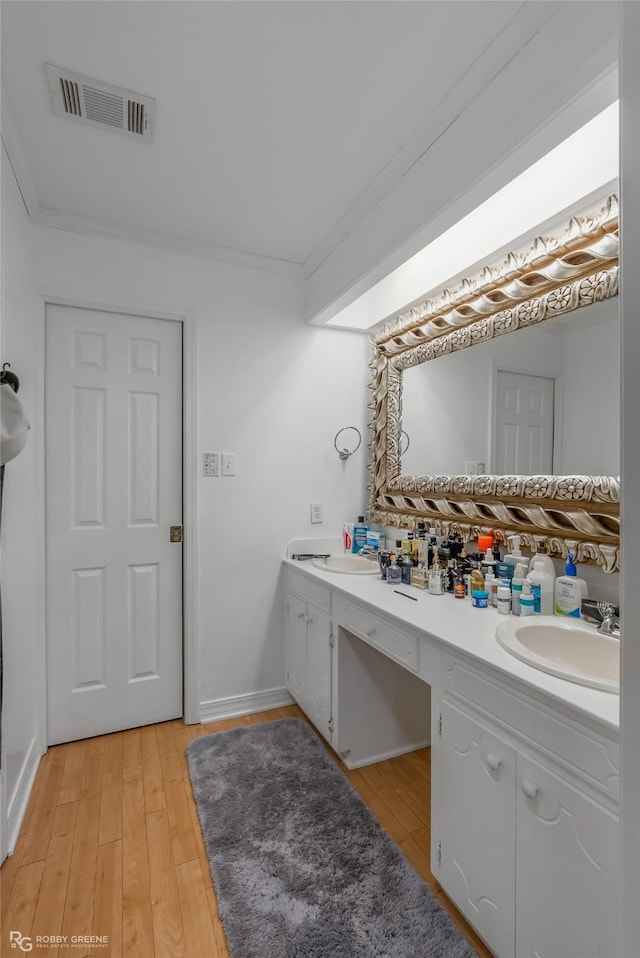 bathroom with vanity, crown molding, and wood-type flooring