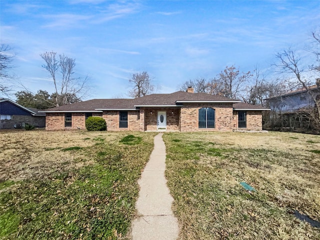 ranch-style home with a front yard, brick siding, and a chimney