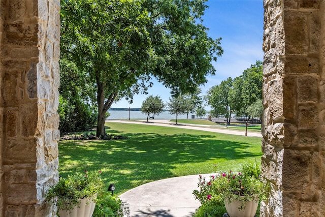 surrounding community with a water view and a lawn