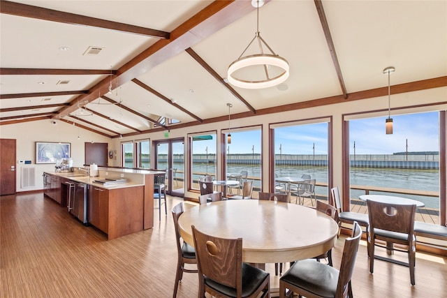 dining room with sink, a water view, lofted ceiling with beams, and light hardwood / wood-style floors