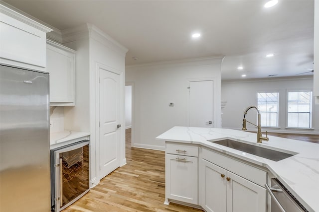 kitchen with white cabinetry, appliances with stainless steel finishes, sink, and beverage cooler