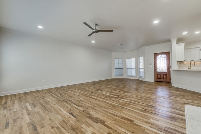 unfurnished living room featuring light hardwood / wood-style floors, ceiling fan, and ornamental molding