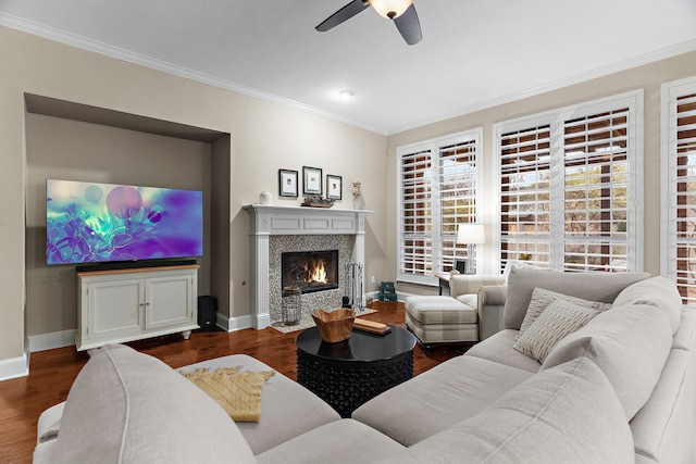 living room featuring dark wood-type flooring, a tile fireplace, crown molding, and ceiling fan