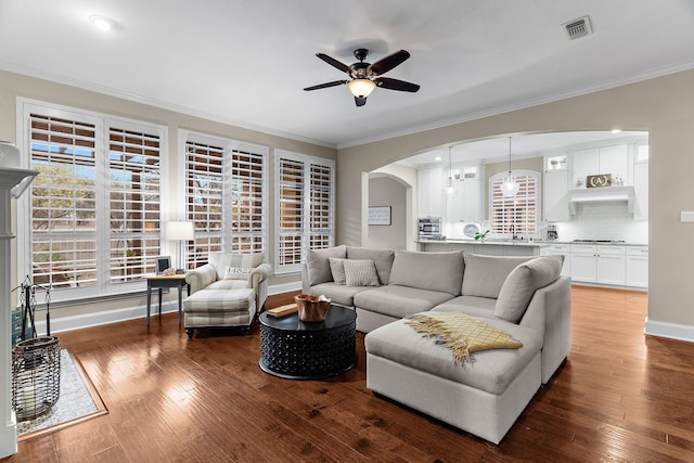 living room featuring ceiling fan, ornamental molding, and dark hardwood / wood-style floors