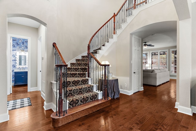 staircase featuring ceiling fan, a towering ceiling, and hardwood / wood-style floors