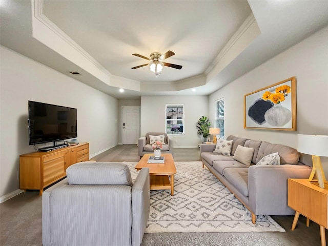 living room with a raised ceiling, ceiling fan, and crown molding