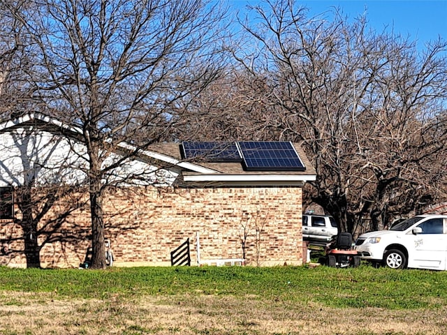 view of side of property featuring a yard and solar panels