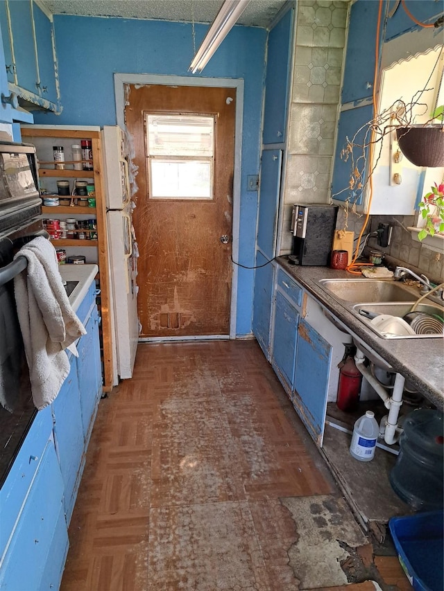 kitchen featuring blue cabinets, sink, and dark parquet floors