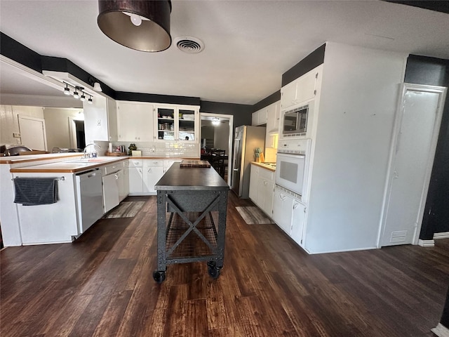 kitchen with dark wood-type flooring, stainless steel appliances, tasteful backsplash, and white cabinets