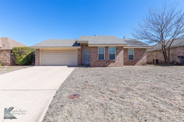 ranch-style house featuring concrete driveway, brick siding, and an attached garage