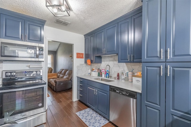 kitchen with stainless steel appliances, light countertops, visible vents, a sink, and blue cabinets