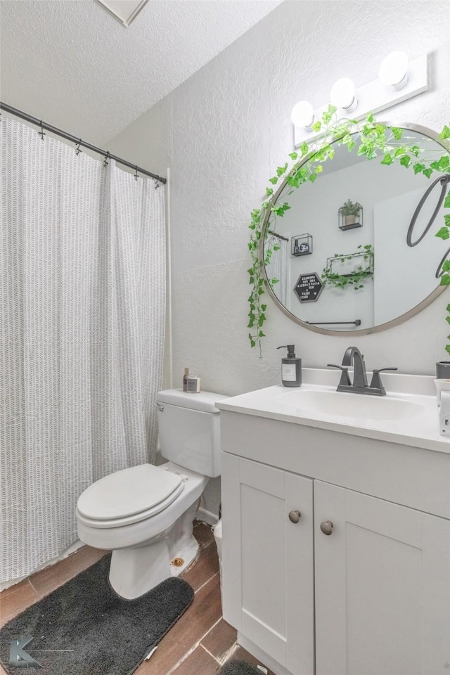 bathroom featuring a textured wall, toilet, a textured ceiling, vanity, and wood finished floors