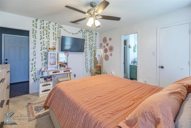 bedroom with visible vents, a ceiling fan, light colored carpet, ensuite bathroom, and a textured ceiling