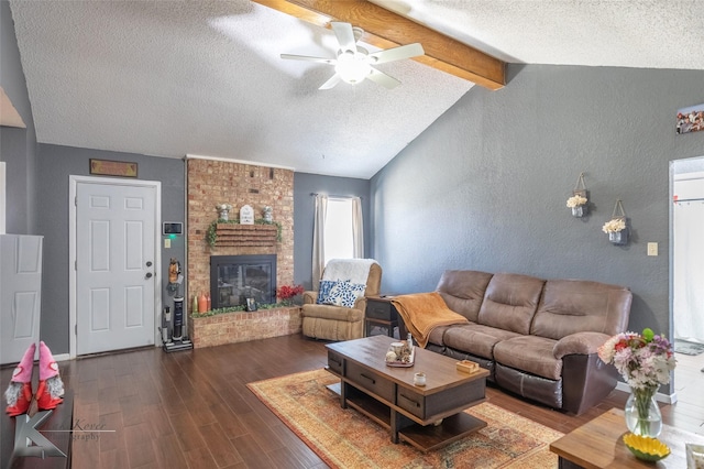 living area featuring a textured wall, dark wood-type flooring, vaulted ceiling with beams, and a fireplace