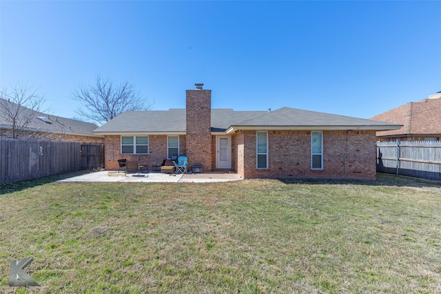 back of property with brick siding, a chimney, a patio area, and a fenced backyard