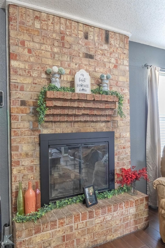 details featuring a fireplace, a textured ceiling, and wood finished floors