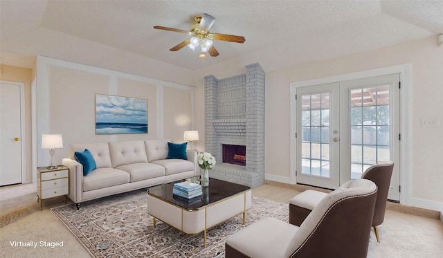 living room with a textured ceiling, french doors, a brick fireplace, and ceiling fan