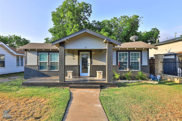 bungalow-style home with brick siding, a front lawn, and fence