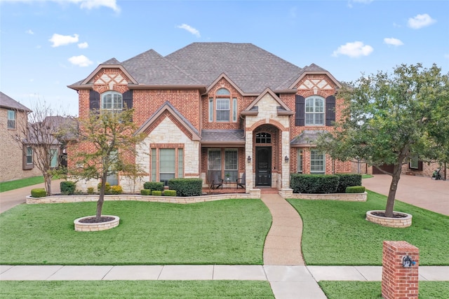 view of front of house featuring a front yard, stone siding, brick siding, and roof with shingles