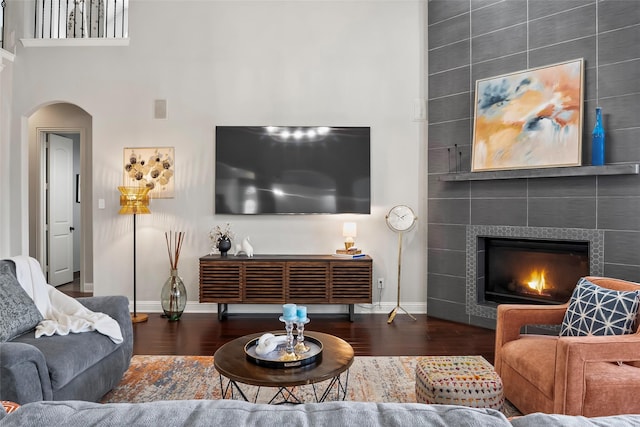 2418 Strathfield Ln, Trophy Club, TX 76262 - living area featuring wood finished floors, a tiled fireplace, baseboards, and arched walkways