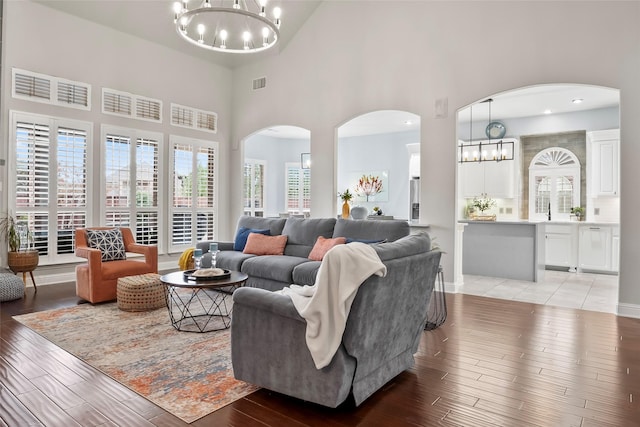 living room featuring light wood-style flooring, visible vents, and an inviting chandelier