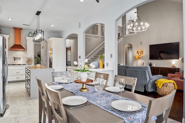 dining area featuring arched walkways, recessed lighting, a notable chandelier, visible vents, and stairway