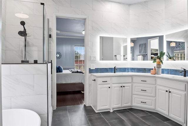 ensuite bathroom featuring connected bathroom, a tile shower, a sink, and double vanity