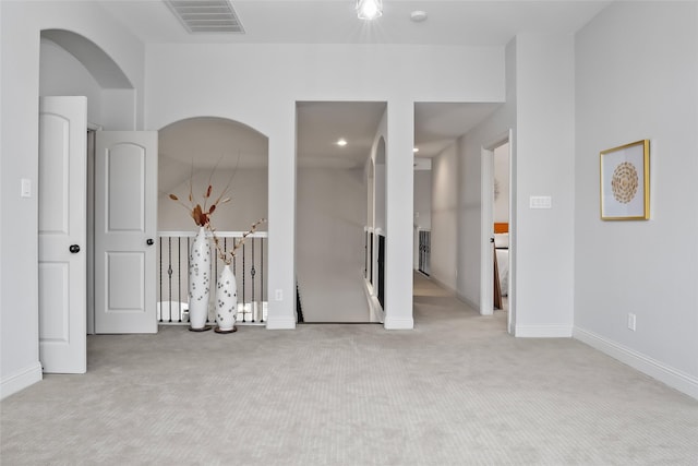 spare room with baseboards, visible vents, and light colored carpet