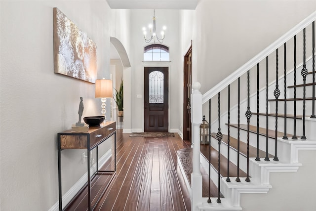 entrance foyer featuring dark wood finished floors, stairway, a high ceiling, an inviting chandelier, and baseboards