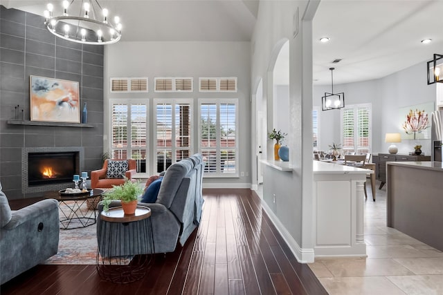 living area with a tile fireplace, a notable chandelier, visible vents, baseboards, and light wood-style floors