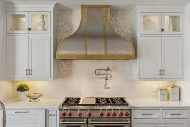 kitchen with decorative backsplash, white cabinetry, wall chimney exhaust hood, and double oven range