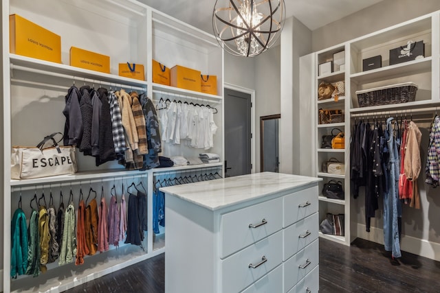 walk in closet with dark wood-type flooring and a notable chandelier