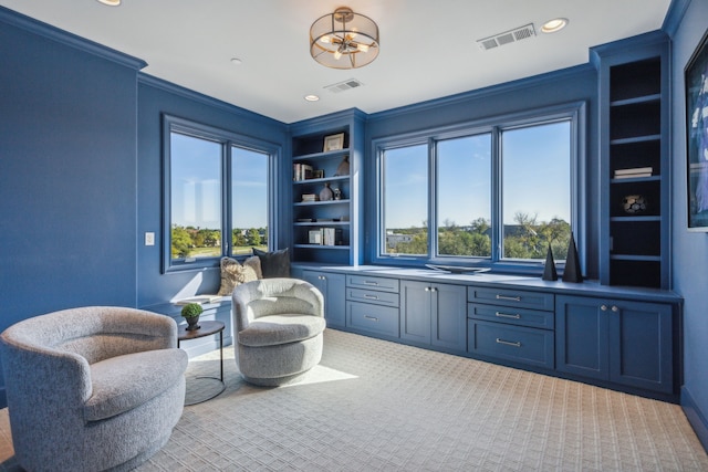 sitting room with ornamental molding, light colored carpet, and built in features