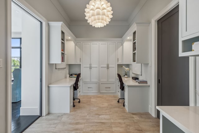 office area with a chandelier, crown molding, and built in desk