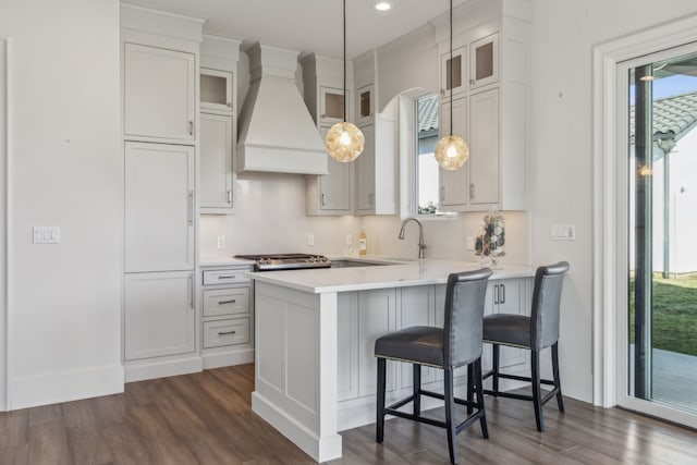 kitchen featuring hanging light fixtures, white cabinetry, dark hardwood / wood-style flooring, and custom range hood