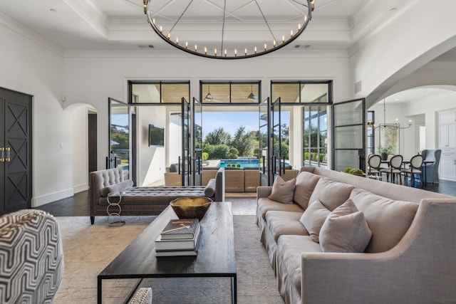 living room featuring wood-type flooring, an inviting chandelier, crown molding, and a towering ceiling