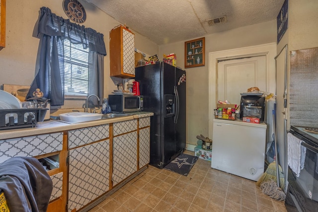 kitchen featuring sink, a textured ceiling, and black appliances