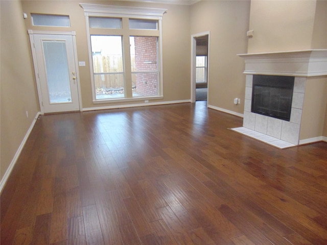 unfurnished living room featuring a tiled fireplace and dark hardwood / wood-style flooring