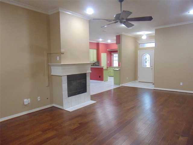 unfurnished living room featuring hardwood / wood-style floors, ceiling fan, crown molding, and a fireplace