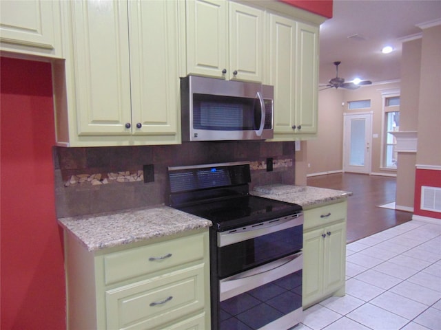 kitchen with light tile patterned floors, tasteful backsplash, double oven range, and light stone counters