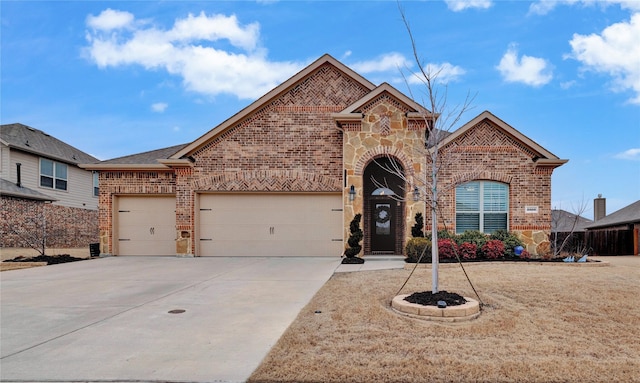 french country inspired facade with an attached garage, stone siding, concrete driveway, and brick siding