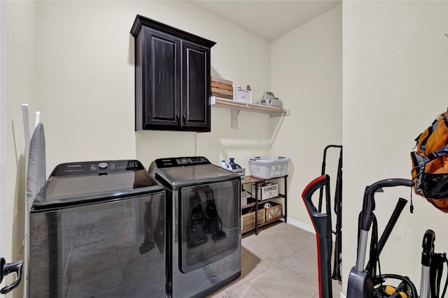 washroom featuring light tile patterned floors, separate washer and dryer, cabinet space, and baseboards