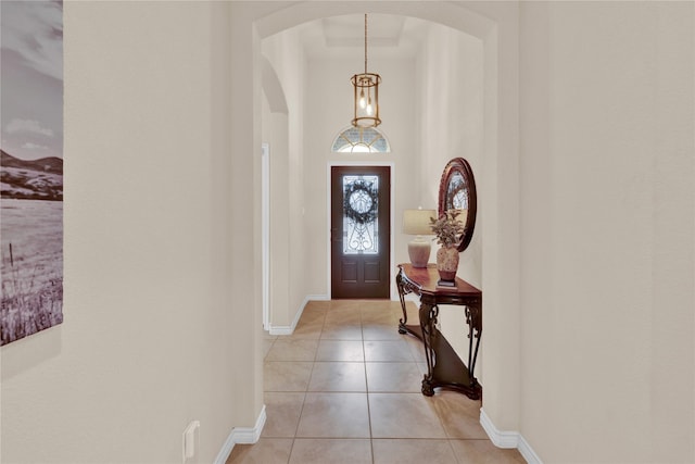 foyer entrance with arched walkways, baseboards, and light tile patterned floors